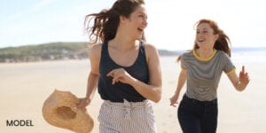 Mother and Daughter Smiling and Running Down Beach